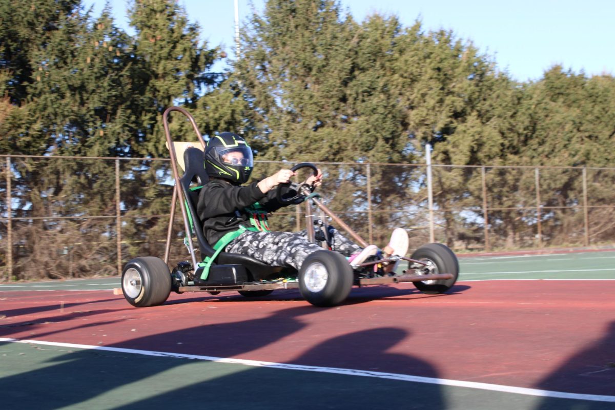 A Supermileage Member demonstrates their driving on the Tennis Court.